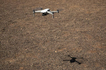 Drone flying over brown terrain full of pebbles - JMF00616