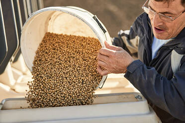 Farmer filling machine with soybean seeds at farm - NOF00499