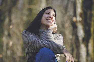 Cheerful young beautiful woman in forest on sunny day - OMIF00778