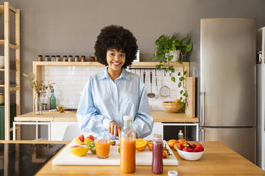 Happy beautiful woman with fruits standing in kitchen at home - OIPF01716