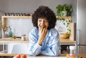 Schöne Frau isst Erdbeere lehnt auf Kücheninsel zu Hause - OIPF01725