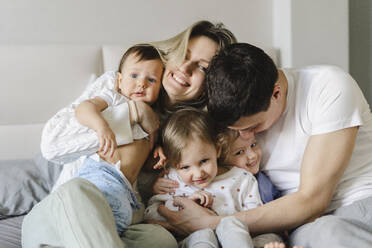 Parents embracing children sitting on bed at home - SEAF00867