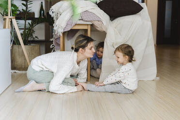 Mutter sieht Tochter im Wohnzimmer sitzend an - SEAF00879