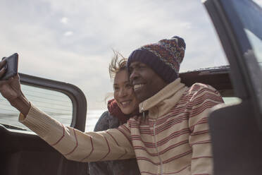 Glückliches Paar macht Selfie auf der Rückbank eines Autos - CAIF32354