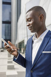 Smiling businessman looking at smart phone - IFRF01624