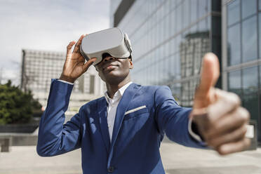 Businessman wearing virtual reality simulator showing thumbs up - IFRF01651