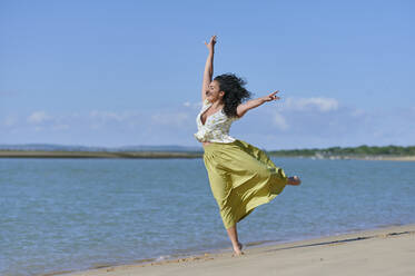 Carefree young woman enjoying dance at beach - KIJF04463