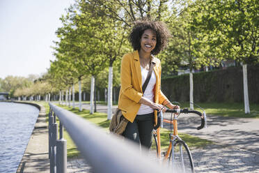 Happy businesswoman with bicycle by River Main - UUF25942