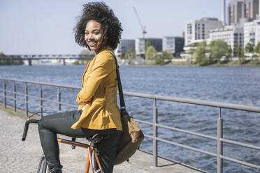 Smiling businesswoman with bicycle by River Main - UUF25946