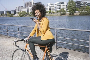 Happy businesswoman sending voicemail through smart phone by River Main - UUF25948