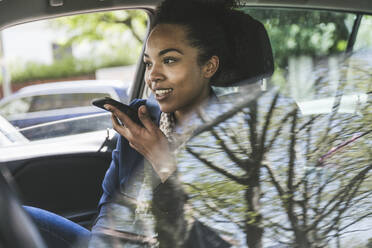 Businesswoman sending voicemail through smart phone sitting in car - UUF25972