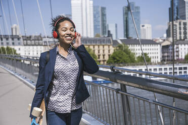 Businesswoman listening music through wireless headphones by River Main - UUF25990