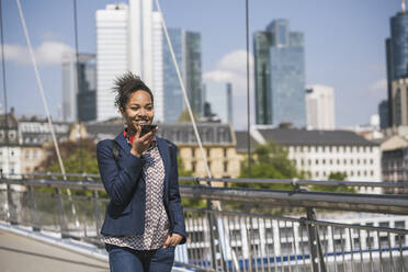 Smiling businesswoman sending voicemail through smart phone - UUF25993