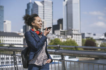 Junge Geschäftsfrau, die eine Voicemail über ihr Mobiltelefon verschickt - UUF25994