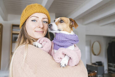 Frau mit Wollmütze zu Hause mit Hund und Schal - KMKF01813