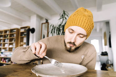 Hungriger Mann kratzt letzten Reiskorn von seinem Teller - KMKF01834