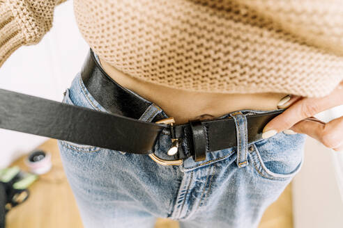 Wickede, NRW, Germany: A young woman fastens a belt - KMKF01838