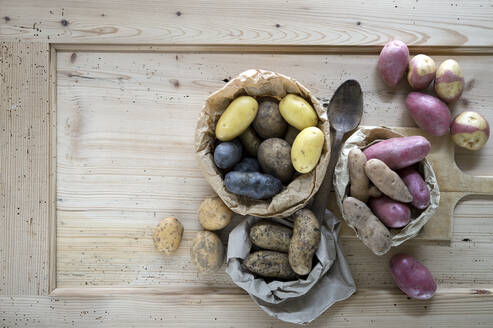 Different varieties of raw potatoes on rustic wooden background - ASF06823