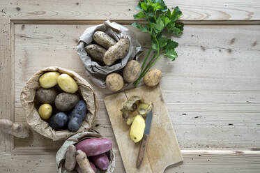 Parsley and different varieties of raw potatoes on rustic wooden background - ASF06824