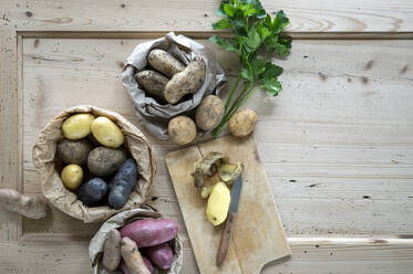 Petersilie und verschiedene Sorten von rohen Kartoffeln auf rustikalem Holzhintergrund - ASF06824