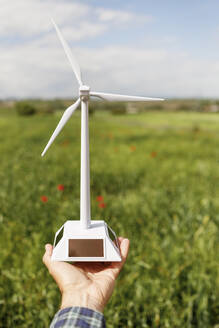 Mann hält Prototyp einer Windkraftanlage auf einer grünen Wiese - IFRF01655