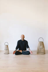 Mann sitzt im Lotussitz und meditiert im Yogastudio - MMPF00042