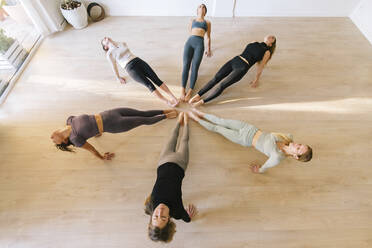 Frauen üben Yoga im Kreis in einem Fitnessstudio - MMPF00052