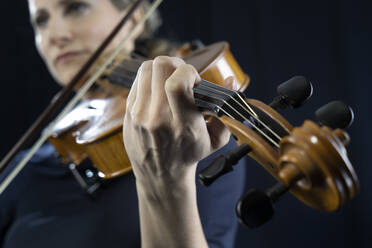 Ältere Frau spielt Geige vor schwarzem Hintergrund - RNF01350