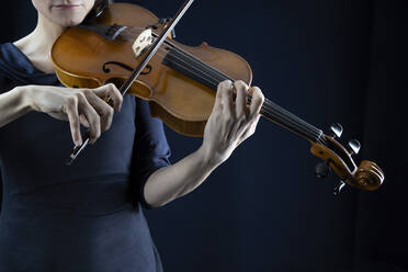Mature woman playing violin in front of black background - RNF01351