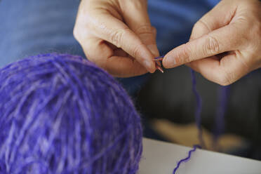 Hands of man knitting with purple wool - AZF00396