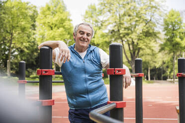 Glücklicher älterer Mann inmitten einer Gymnastikstange im Park - UUF26065