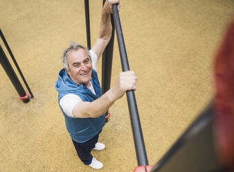 Lächelnder älterer Mann mit Gymnastikstange im Park - UUF26070