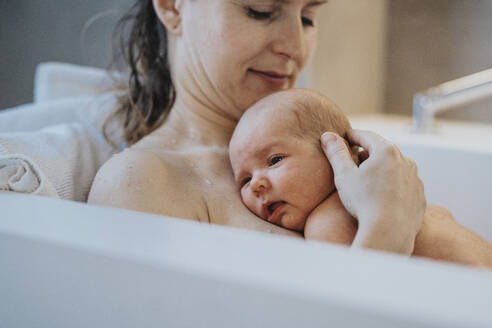 Ein kleiner Junge liegt auf der Brust seiner Mutter in der Badewanne zu Hause - MFF09093