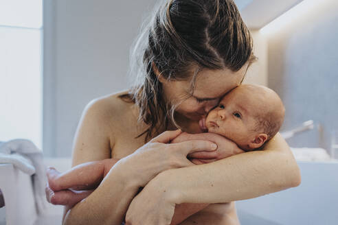Naked mother cuddling cute baby in bathtub at home - MFF09108