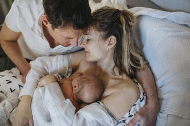 Vater umarmt Frau und Sohn, die zu Hause auf dem Bett liegen - MFF09110