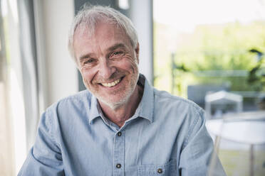 Happy senior man with gray hair sitting at home - UUF26100