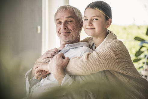 Glückliche Enkelin, die ihren Großvater zu Hause umarmt - UUF26154