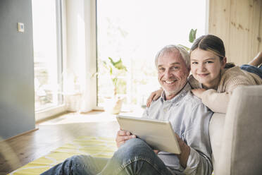 Glücklicher älterer Mann und Enkelin mit Tablet-PC zu Hause - UUF26166
