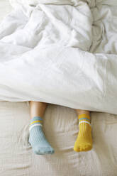 Frau mit blauen und gelben Socken im Bett - TYF00145