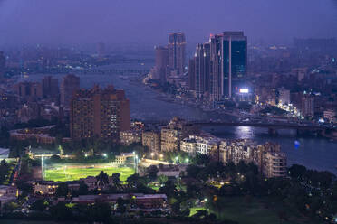 Ägypten, Kairo, Fluss Nil, Beleuchteter Stadtpark in der Abenddämmerung mit Nil und Wolkenkratzern im Hintergrund - TAMF03342