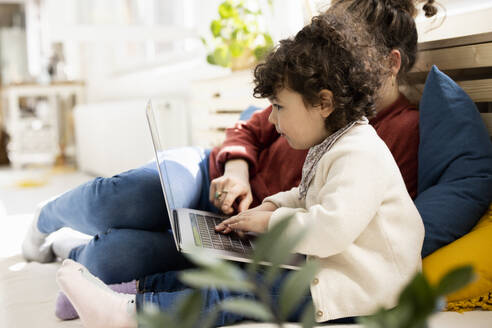 Kleines Mädchen mit Laptop auf dem Schoß der Mutter auf der Couch zu Hause - JOSEF09416