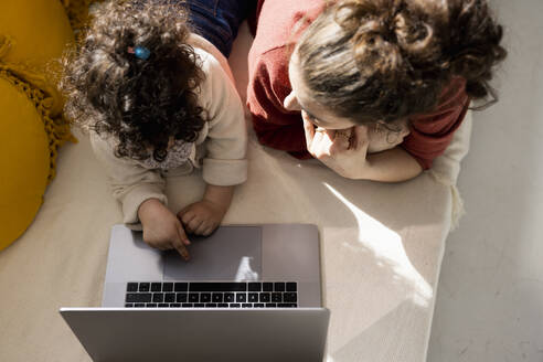 Kleines Mädchen mit Laptop neben der Mutter auf der Couch zu Hause - JOSEF09417