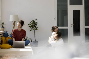 Junge Frau arbeitet von zu Hause aus, während das Kindermädchen mit ihrer Tochter spielt - JOSEF09426