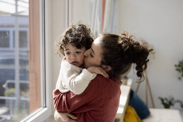 Mutter hält und kuschelt kleine Tochter zu Hause - JOSEF09435