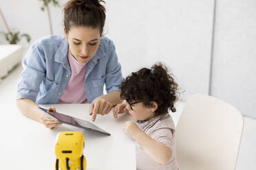 Arbeitende Mutter sitzt am Tisch Tochter spielt mit AI Spielzeugroboter - JOSEF09442