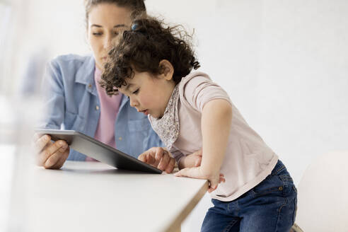 Kleines Mädchen schaut auf ein digitales Tablet, das von der Mutter gehalten wird - JOSEF09446