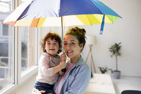 Mutter und Tochter stehen zu Hause und halten einen Regenschirm - JOSEF09451