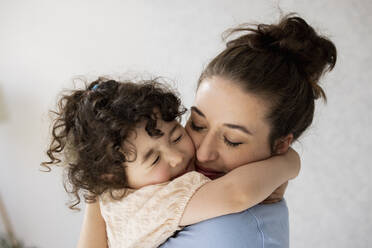 Happy mother and daughter hugging with eyes closed - JOSEF09455