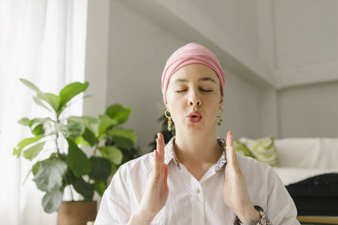 Woman with eyes closed doing breathing exercise in living room at home - SEAF00903