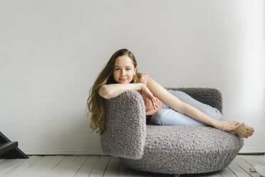 Smiling woman sitting on armchair at home - SEAF00930